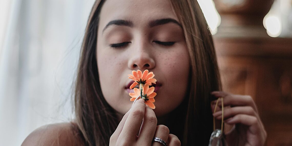 Portrait of woman kissing orange flowers
